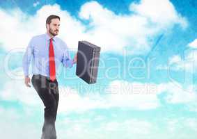 Businessman holding briefcase in sky clouds