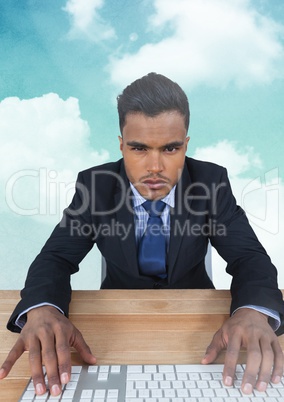 Businessman using keyboard in cloudy sky