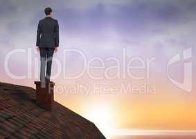 Businessman on roof chimney with sunset