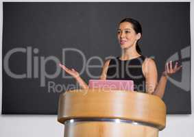 Businesswoman on podium speaking at conference with board
