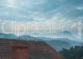 Roof with chimney and misty mountain landscape