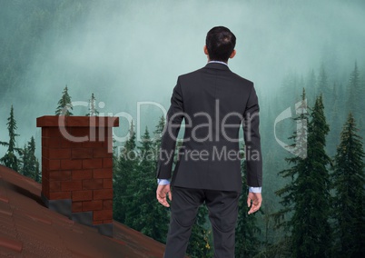 Businessman standing on Roof with chimney and misty forest