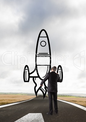 Business man drawing a rocket on the road