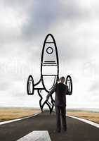 Business man drawing a rocket on the road
