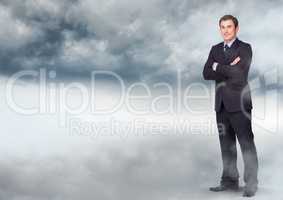 Businessman folding arms in cloudy sky