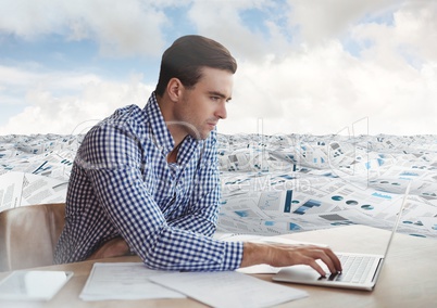 Businessman at desk in sea of documents under sky clouds