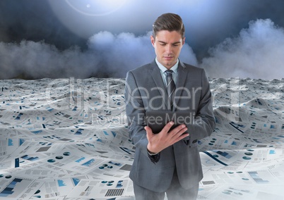 Businessman on tablet in sea of documents under sky clouds