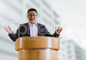 Businessman on podium speaking at conference with buildings