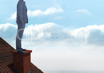 Businessman standing on Roof with chimney and cloudy sky