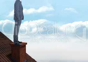Businessman standing on Roof with chimney and cloudy sky