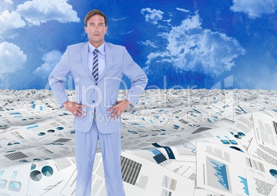 Businessman in sea of documents under sky clouds