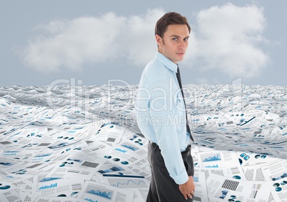 Businessman in sea of documents under sky clouds