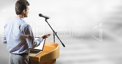 Businessman on podium speaking at conference with bright background