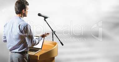 Businessman on podium speaking at conference with bright background