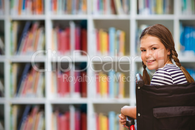 Composite image of girl sitting in wheelchair in school