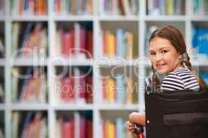 Composite image of girl sitting in wheelchair in school