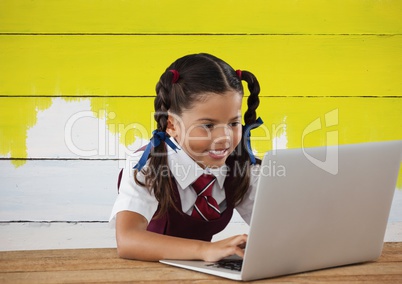 Schoolgirl on laptop with yellow painted background