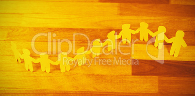 Yellow paper cutout human chain on wooden table