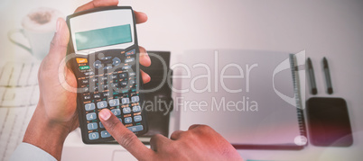 Composite image of cropped hands of businessman using calculator