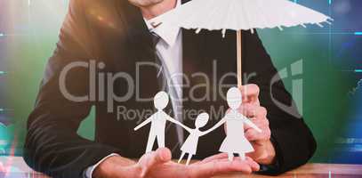 Composite image of businessman holding umbrella and paper family