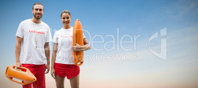 Composite image of portrait of lifeguards holding rescue buoy