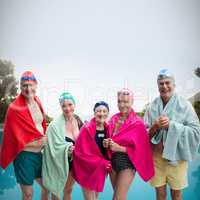 Composite image of portrait of senior friends in swimwear covered with towels