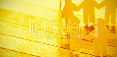 Yellow paper figures holding hands on wooden table