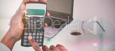 Composite image of hands of businessman using calculator