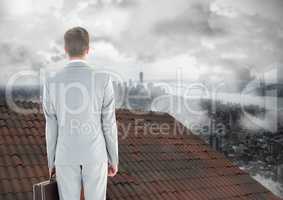 Businessman standing on Roof with chimney and misty city
