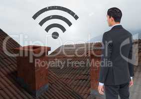 Wi-fi icon and Businessman standing on Roofs with chimney and fog