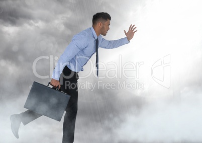 Businessman holding briefcase in grey sky