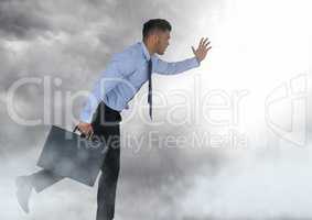 Businessman holding briefcase in grey sky