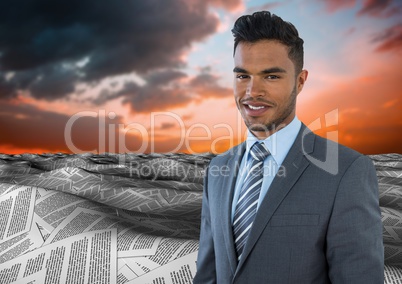 Businessman in sea of documents under twilight sky clouds