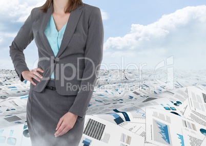 Businesswoman in sea of documents under sky clouds