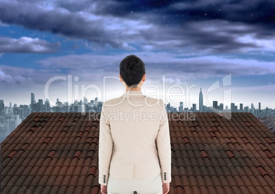 Businesswoman standing on Roof with city sky