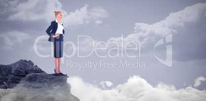 Composite image of businesswoman standing with hands on hips