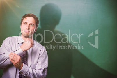 Composite image of portrait of young businessman adjusting shirt sleeves