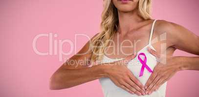 Mid section of young woman with ribbon touching breast