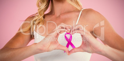 Mid section of woman with ribbon making heart shape by hands