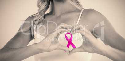 Mid section of woman with ribbon making heart shape by hands
