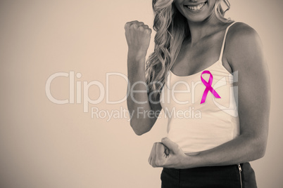 Mid section of woman with pink ribbon clenching fist