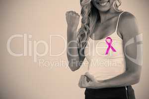 Mid section of woman with pink ribbon clenching fist
