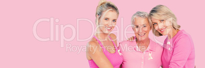 Composite image of portrait of smiling daughters with mother supporting breast cancer social issue