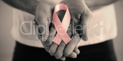 Mid section of woman holding pink ribbon