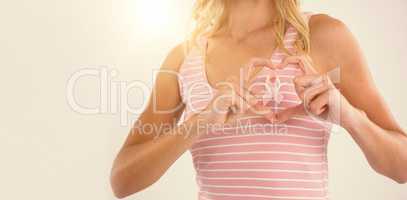 Mid section of young woman making heart shape with hands over ribbon