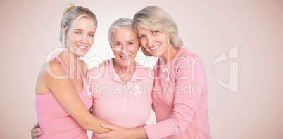 Composite image of portrait of smiling daughters with mother supporting breast cancer awareness