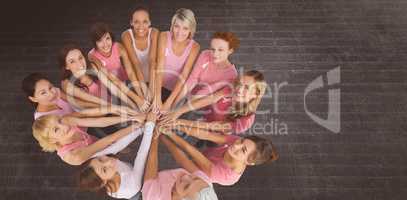 Composite image of portrait of happy female friends supporting breast cancer awareness