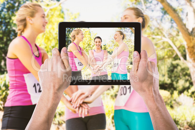 Composite image of cropped hand holding digital tablet