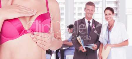 Composite image of mid section of woman in pink bra checking breast for cancer awareness