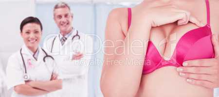 Composite image of mid section of woman in pink bra touching breast for cancer awareness
